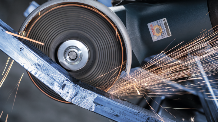 Cutting wheel grinding through metal, creating bright sparks.