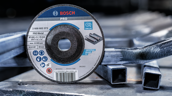 Grinding disc resting on metal pipes in an industrial workshop.