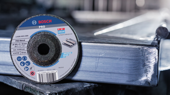 Grinding disc placed on a metal beam in an industrial workshop setting.