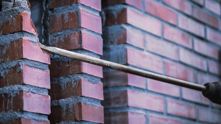 Drill creating a hole through a brick wall.