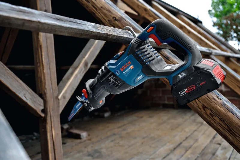 Cordless reciprocating saw resting on a wooden beam at a construction site.