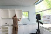 Person aligns wall cabinets using a laser leveling tool in a kitchen installation.