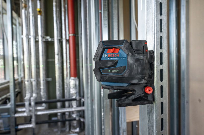 Laser leveling tool mounted on a metal frame, projecting green lines across a construction site.