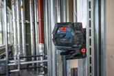 Laser leveling tool mounted on a metal frame, projecting green lines across a construction site.