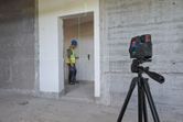 Laser leveling tool projects green lines in a room as a person wearing safety equipment works.