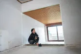 Person operating a laser leveling tool in an unfinished room.