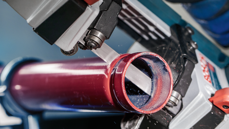 PRO CB4424 Band Saw Blade, 1140 mm, 2 pcs Bandsaw cutting through a metal pipe with visible metal shavings.