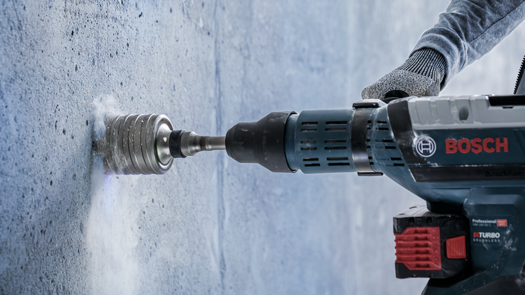 PRO SDS max-5 Core Cutter, 125 x 80 x 97 mm Person wearing safety equipment drills a hole into a concrete wall.