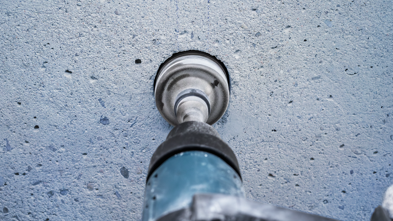 PRO SDS max-5 Core Cutter, 125 x 80 x 97 mm Core drill making a circular hole in a concrete wall.