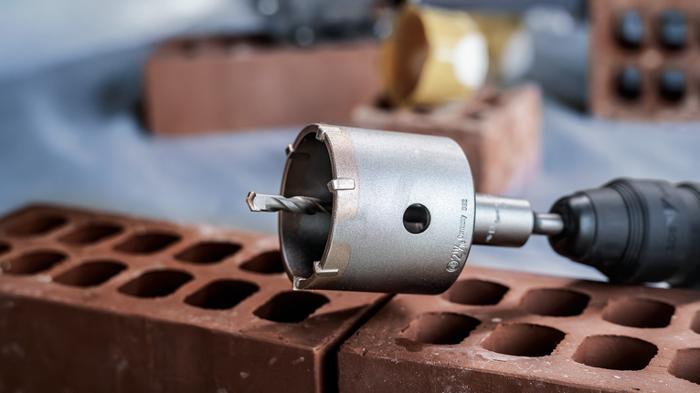 PRO SDS plus-5 Core Cutter, 68 x 50 x 80 mm Core drill bit attached to a power tool positioned on hollow bricks.