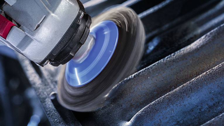 Metal polishing tool spinning against the surface of a steel beam.