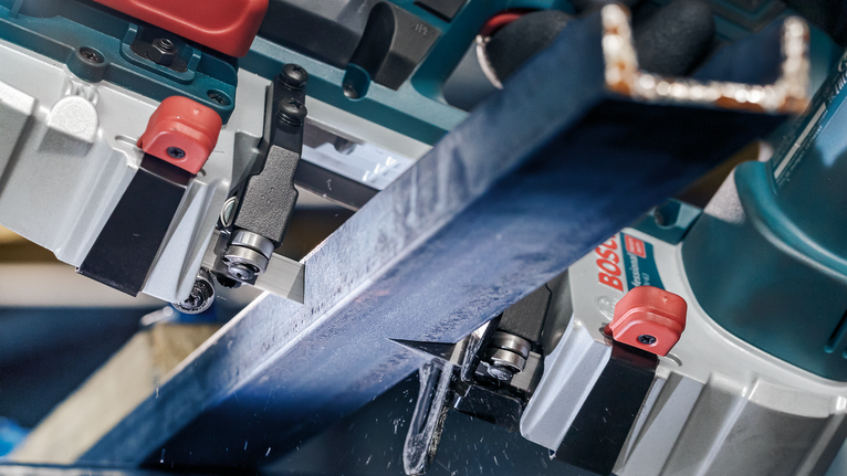 Metal beam being precisely cut by a power saw in an industrial setting.