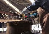 A person wearing safety equipment grinds metal, creating sparks in an industrial setting.