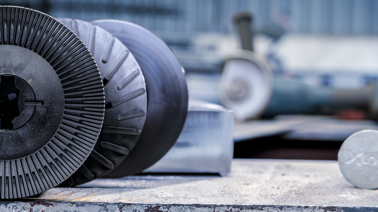 Metal cutting and grinding discs rest on a workbench in an industrial setting.