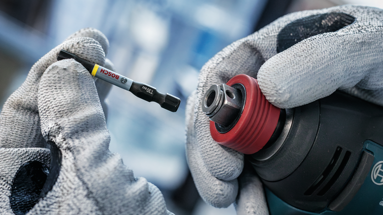 PRO Impact Mixed Set, Display, 6 x 35 pcs Person wearing safety equipment changes a drill bit on a power tool.
