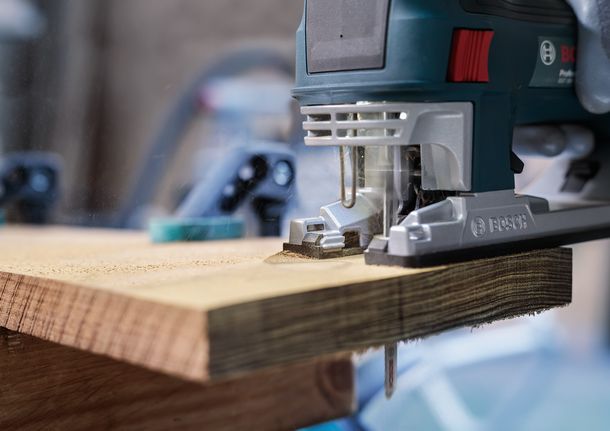 PRO Hardwood clean reverse T101BRF Jigsaw Blade, 100 mm, 5 pcs Jigsaw cutting through a thick wooden plank in a workshop.