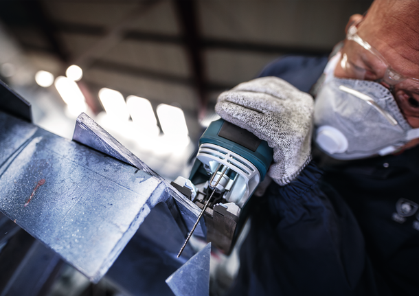 PRO Metal thick and thin T123XF Jigsaw Blade, 100 mm, 5 pcs Person wearing safety equipment uses a jigsaw to cut a metal sheet.