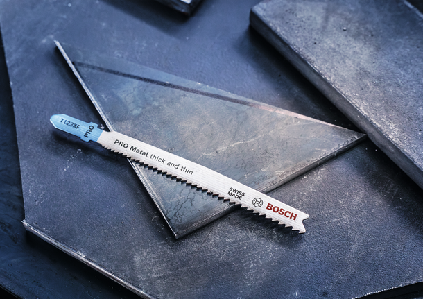 PRO Metal thick and thin T123XF Jigsaw Blade, 100 mm, 5 pcs Metal jigsaw blade resting on dark metal sheets.