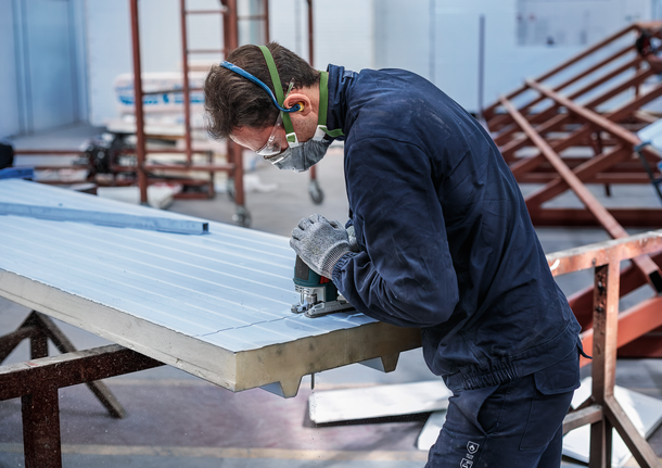 PRO Metal Sandwich T718BF Jigsaw Blade, 180 mm, 3 pcs Person wearing safety equipment uses a jigsaw to cut grooves in an insulated panel.