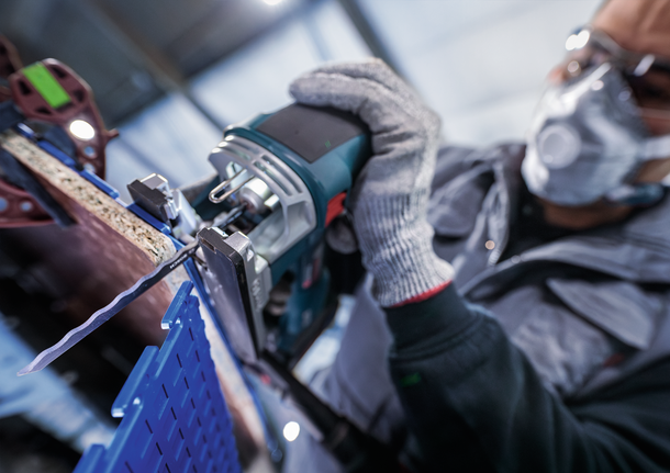 PRO Soft Material T313AW Jigsaw Blade, 152 mm, 3 pcs Person wearing safety equipment cuts a wooden board with a jigsaw.