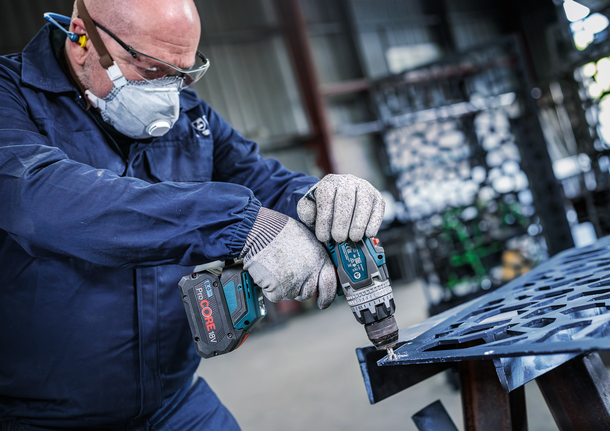 PRO Steel HSS Countersink Bit, 12 x 40 mm, M6 Person wearing safety equipment drills into a metal sheet in an industrial setting.