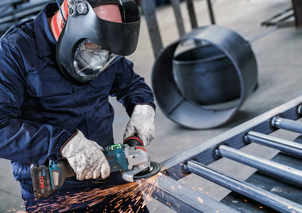 PRO Backing Pad Soft, 125 mm, X-Lock Person wearing safety equipment grinds metal, creating sparks.