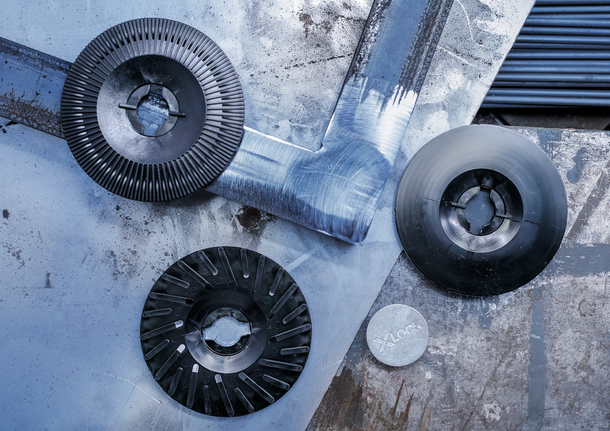 PRO Backing Pad Soft, 125 mm, X-Lock Various abrasive discs and a metal adapter rest on a scratched metal surface.