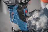 A person wearing safety equipment adjusts the speed setting on a stirring mechanism.