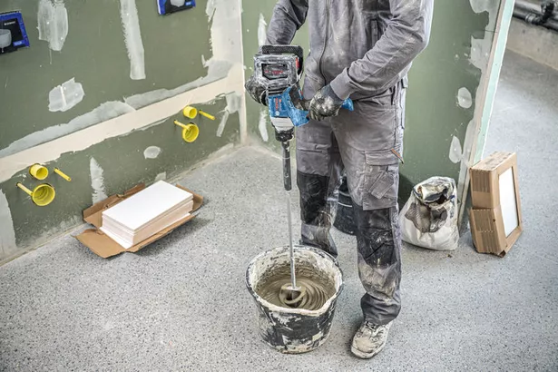 GRW 18V-120 A person wearing safety equipment mixes material in a bucket using a stirring mechanism.