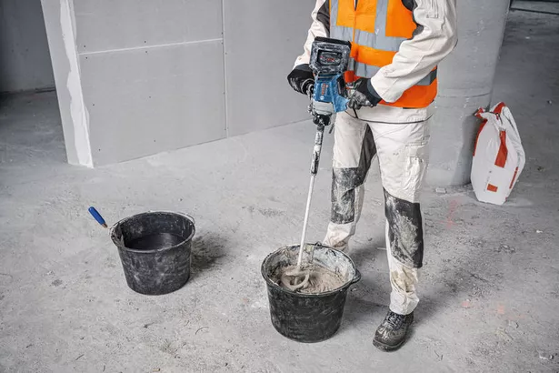GRW 18V-120 A person wearing safety equipment mixes construction material with a stirring mechanism.