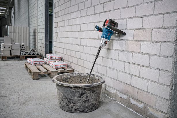 GRW 18V-160 Cordless stirring tool mixes material in a bucket at a construction site.