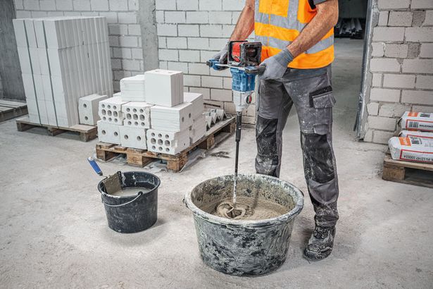 GRW 18V-160 A person wearing safety equipment mixes mortar in a bucket with a stirring mechanism.