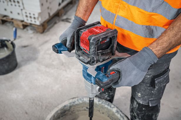 GRW 18V-160 A person wearing safety equipment uses a stirring mechanism to mix material in a bucket.