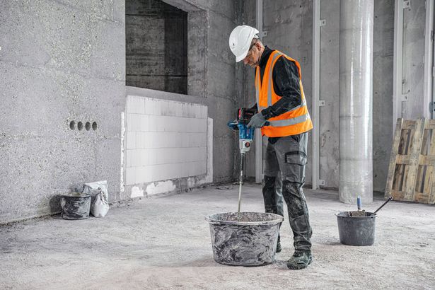 GRW 18V-160 A person wearing safety equipment mixes material with a stirring mechanism on a construction site.