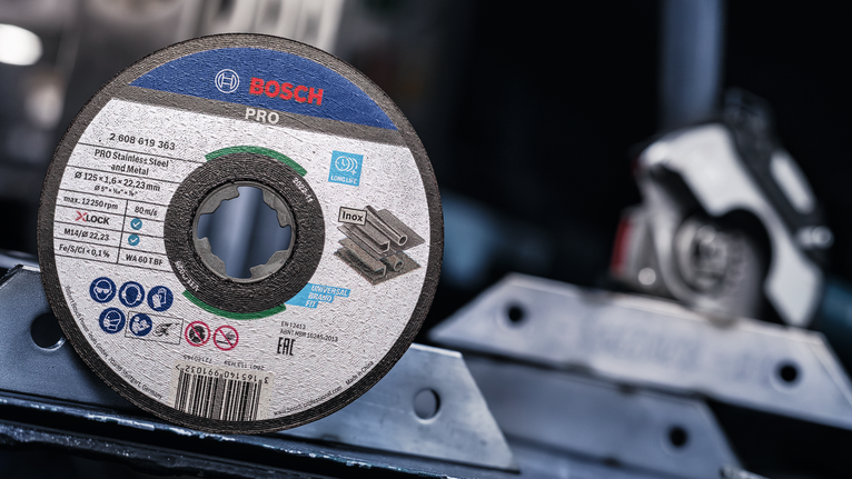 PRO Stainless Steel and Metal Bonded Cutting Disc, 125 x 1.6 x 22.23 mm, X-Lock, Straight, oSa Cutting disc for stainless steel placed on a metal surface in a workshop.
