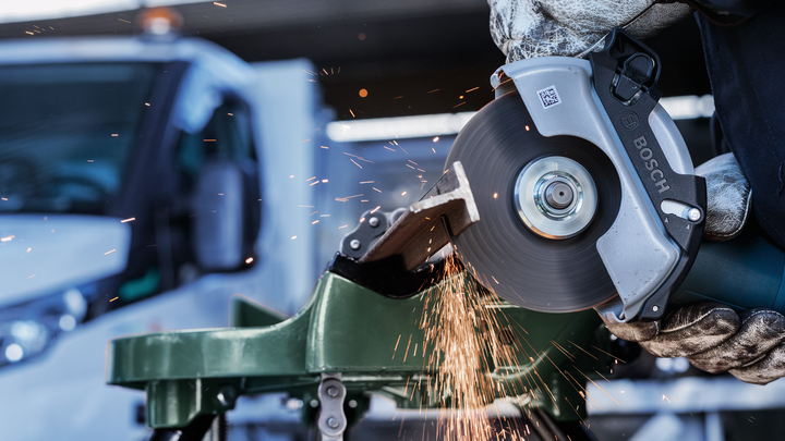 Object #200483039: 3089912_app_web_9 Person wearing safety equipment cuts metal with a power tool, creating sparks.
