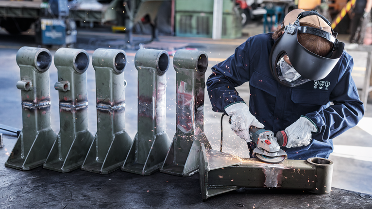 PRO Metal Bonded Grinding Disc, 125 x 6 x 22.23 mm, X-Lock Person wearing safety equipment grinds metal parts, producing sparks in a workshop.