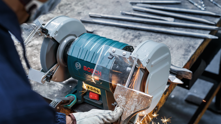PRO Metal Grinding Wheel, 200 x 25 x 32 mm, G46 A worker wearing safety equipment grinds a metal piece with a bench grinder.