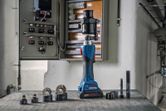 Cordless hydraulic punching tool with various attachments placed near an open control panel.