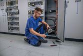 A person wearing safety equipment crimps a cable using a cordless hydraulic tool.