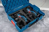 Cordless drill and impact driver set arranged in a blue carrying case.