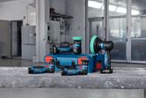 Cordless polishers and a blue toolbox displayed on a workbench in a workshop.
