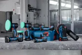 Cordless polishing and sanding tools with blue storage case on a workbench in a workshop.