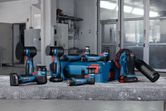 Cordless polishers and accessories arranged on a workbench in an industrial workshop.