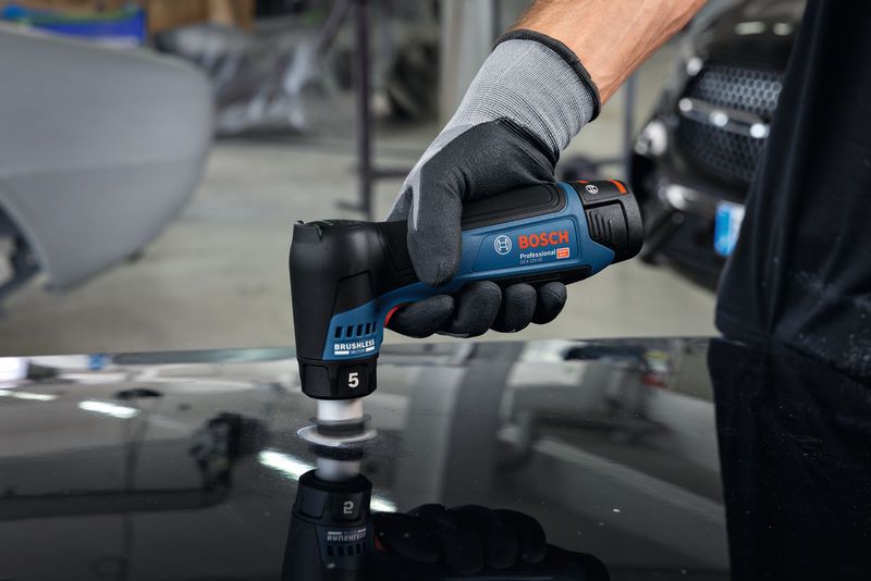 Person wearing safety equipment uses a cordless sander to polish a car surface.