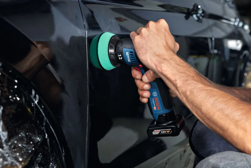 A person polishes a black car door using a cordless polisher.