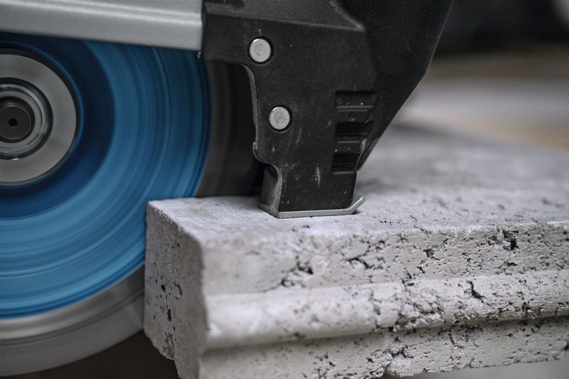 Large angle grinder cutting through a thick concrete slab.