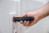 A person uses a non-contact voltage tester near an electrical socket.