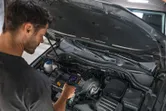 A person inspects a car engine using a thermo camera.