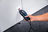 A person uses a voltage tester to check an electrical outlet.